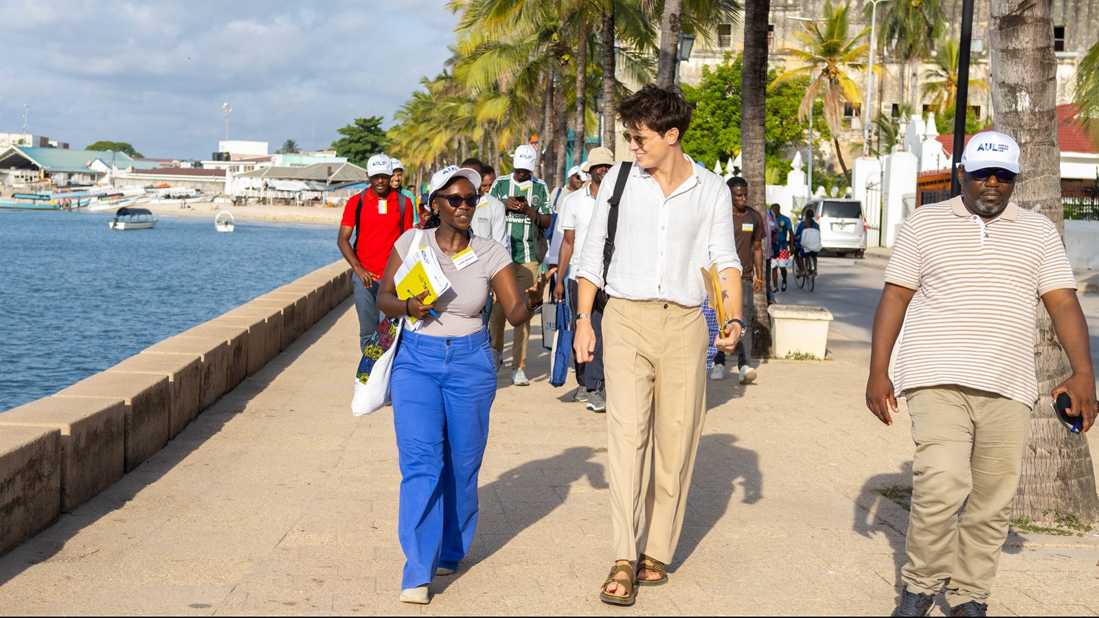 Oliver Harman walking along the Stone Town seafront with Africa Urban Lab students